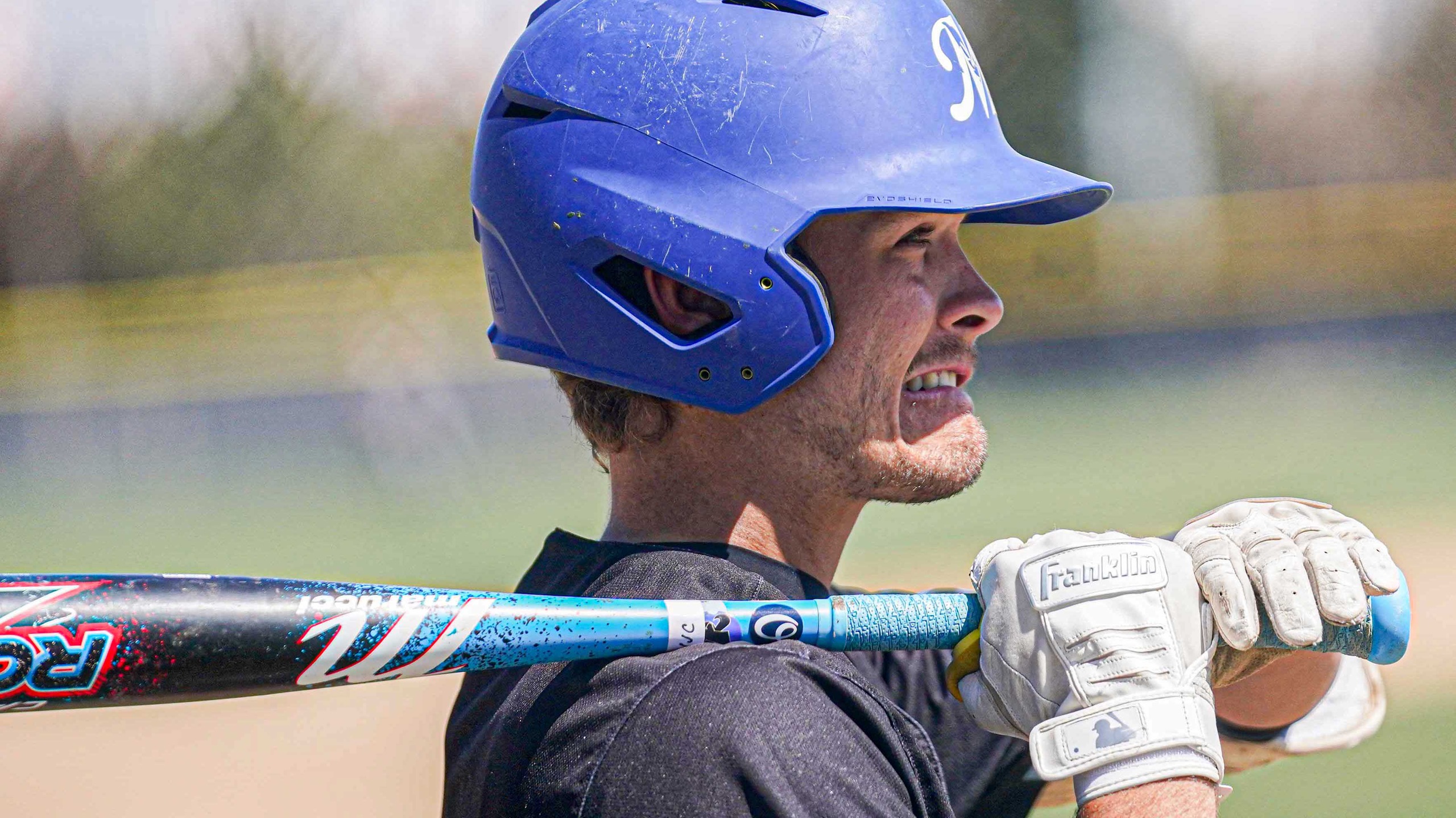 College baseball player in the on-deck circle getting ready to bat.