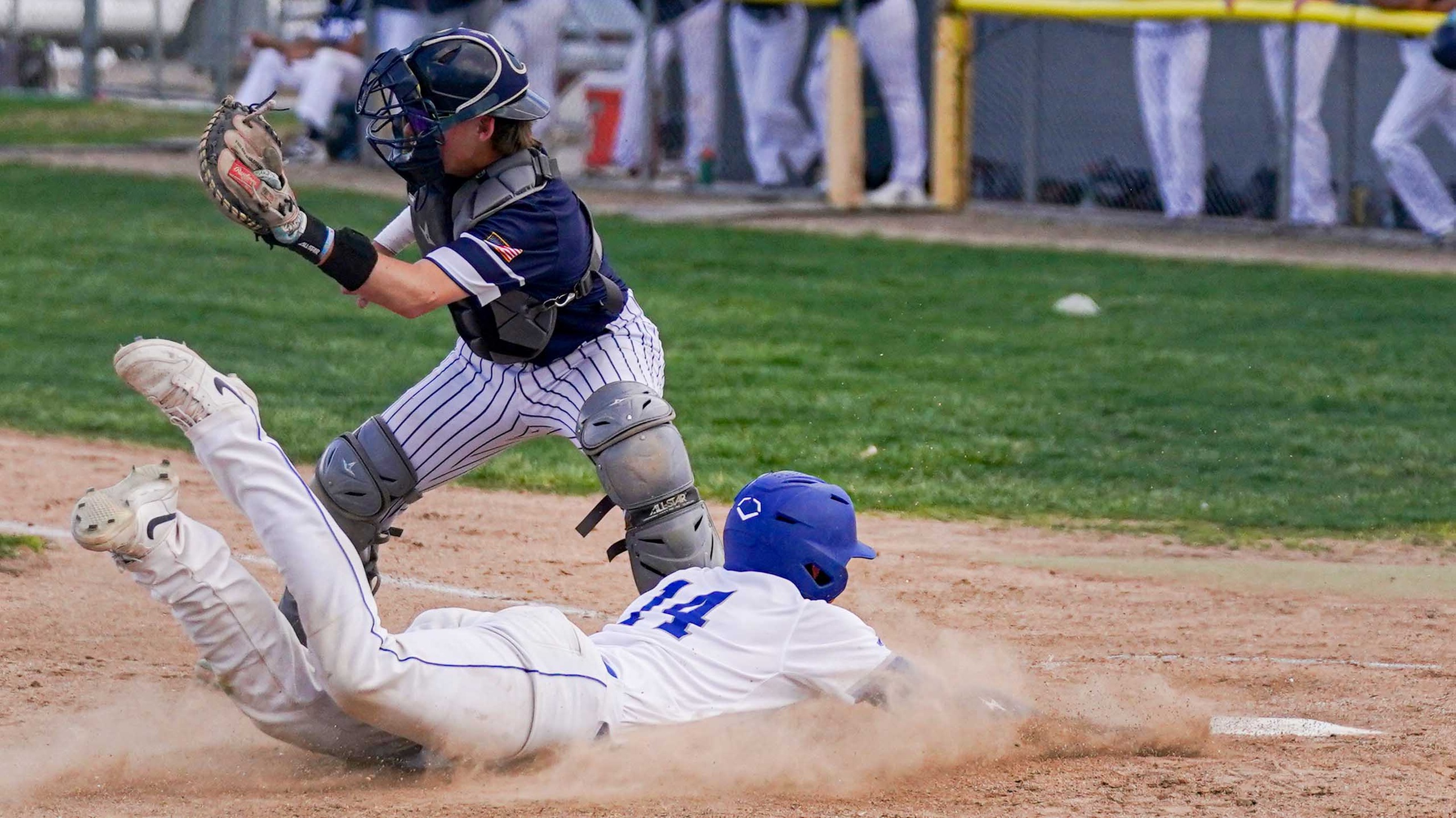 Baseball player sliding into home plage.