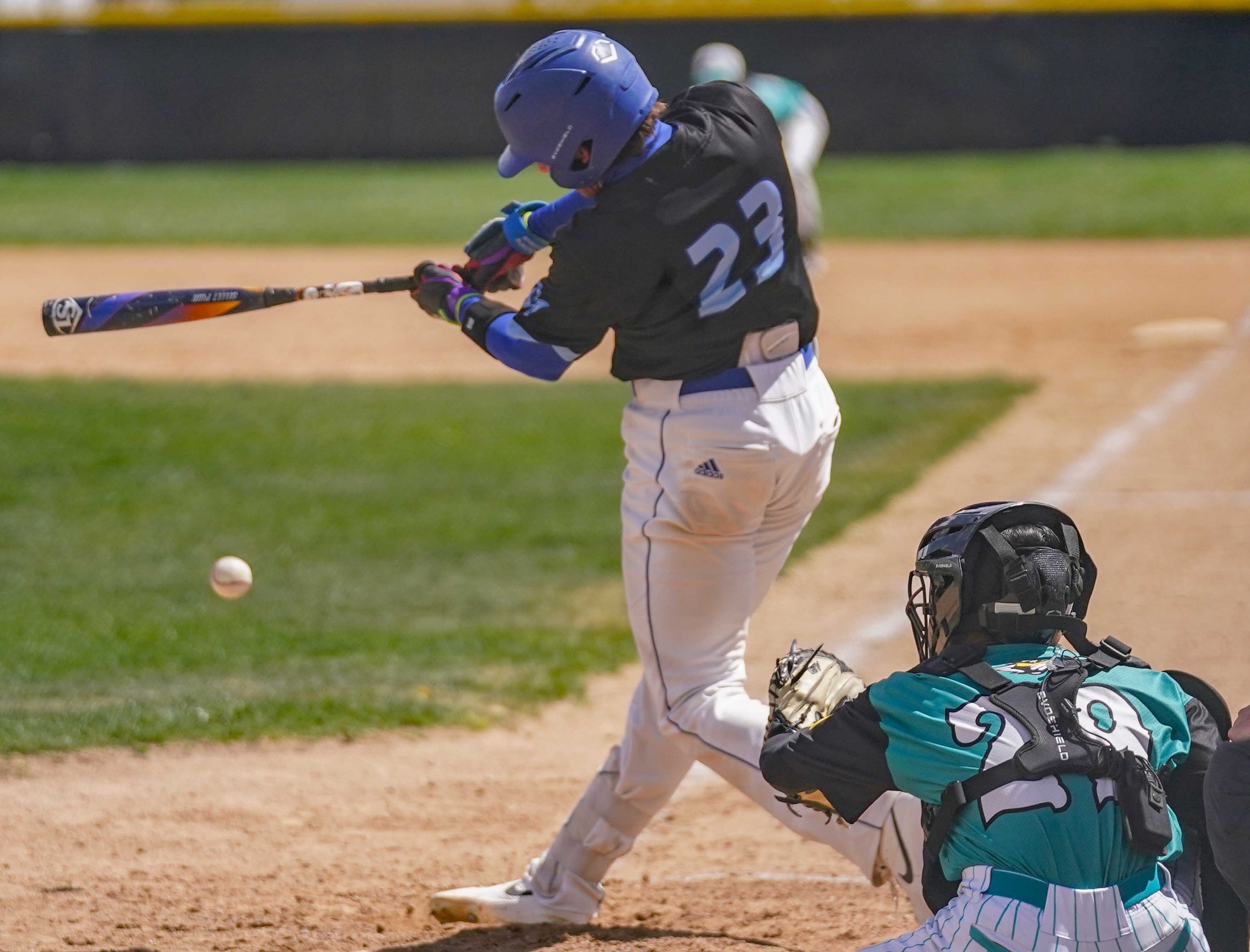 College baseball player hitting the ball.